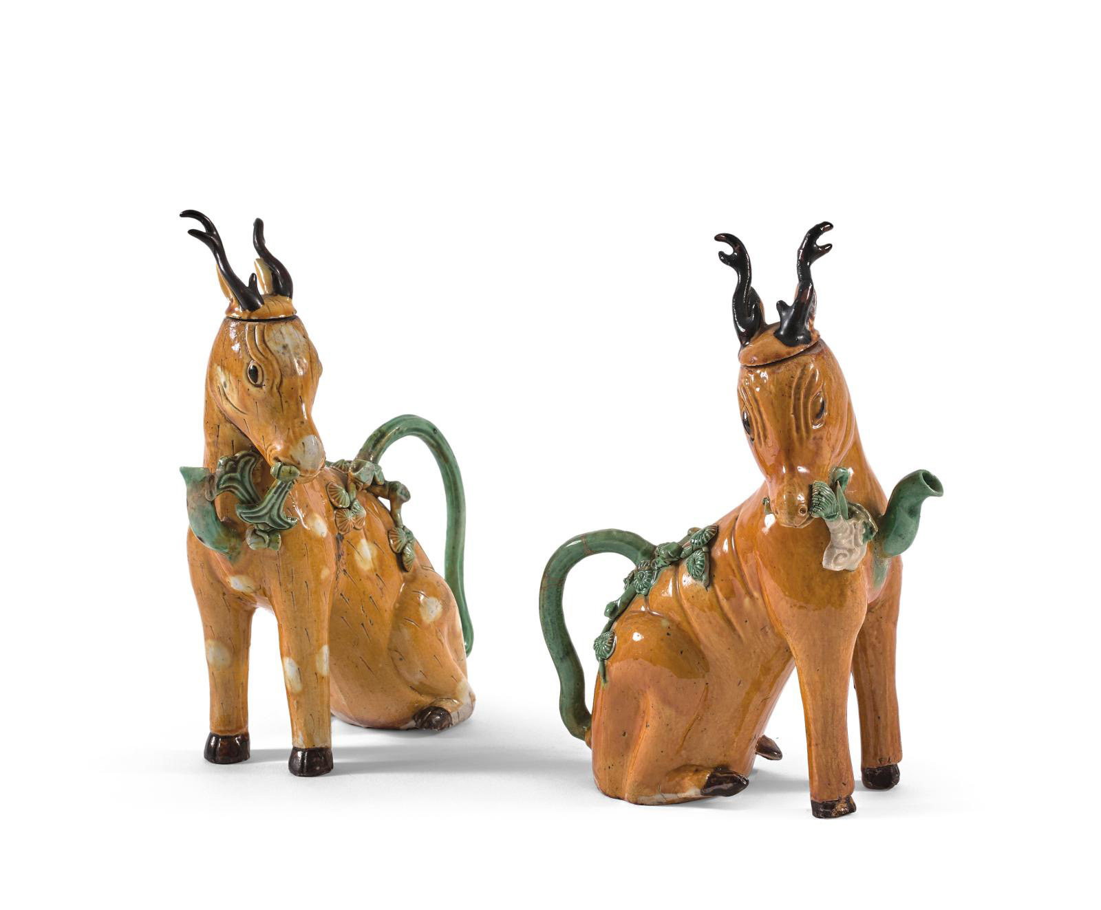 This Kangxi period pair of yellow, brown and green enameled biscuit pitchers shaped like seated deer (h. 22.5 cm/8.85 in) with a handle si
