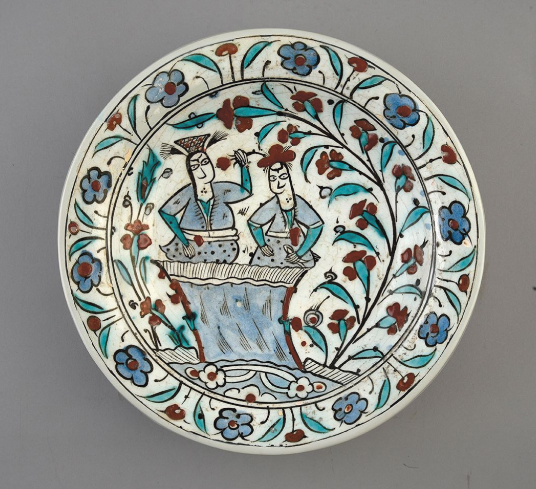 61 824 € Iznik, XVIIe siècle, plat en faïence à décor de deux personnages dans des encadrements de fleurs, diam : 31,2 cm.Drouot, 3 juin 2