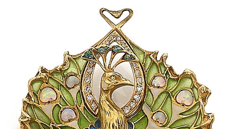 Broche en or jaune stylisée d’un paon, l’aigrette sertie d’émeraudes, dans un encadrement... Dans la roue d’or de l’art nouveau