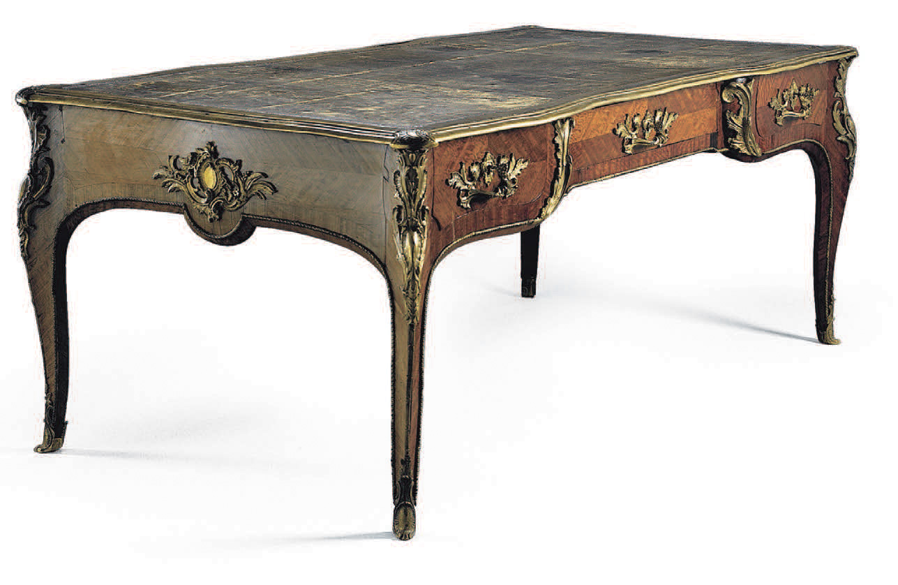Bureau plat en placage d’amarante, à décoration en bronze au C couronné. Époque Louis XV. Attribué à Pierre II Migeon H. 75, l. 196, P. 99 cm.Paris, A