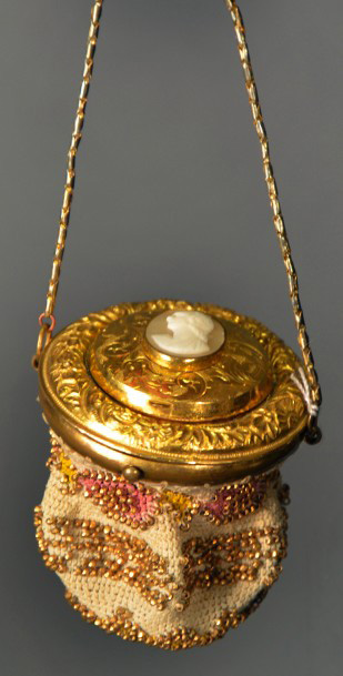 150 €Vers 1850-1860. Bourse en sablé de perles, couvercle en pomponne à frise fleurie s’ouvrant sur un second couvercle serti d’un camé coquille décou