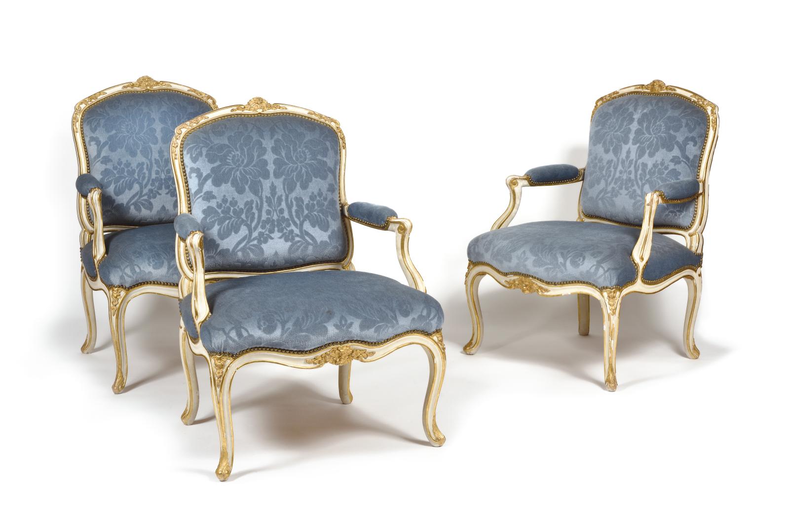 Cette suite de six fauteuils en bois peint et doré (94 x 67 cm), dont le dossier plat et arrondi s’orne sobrement de feuillages, d’agrafes