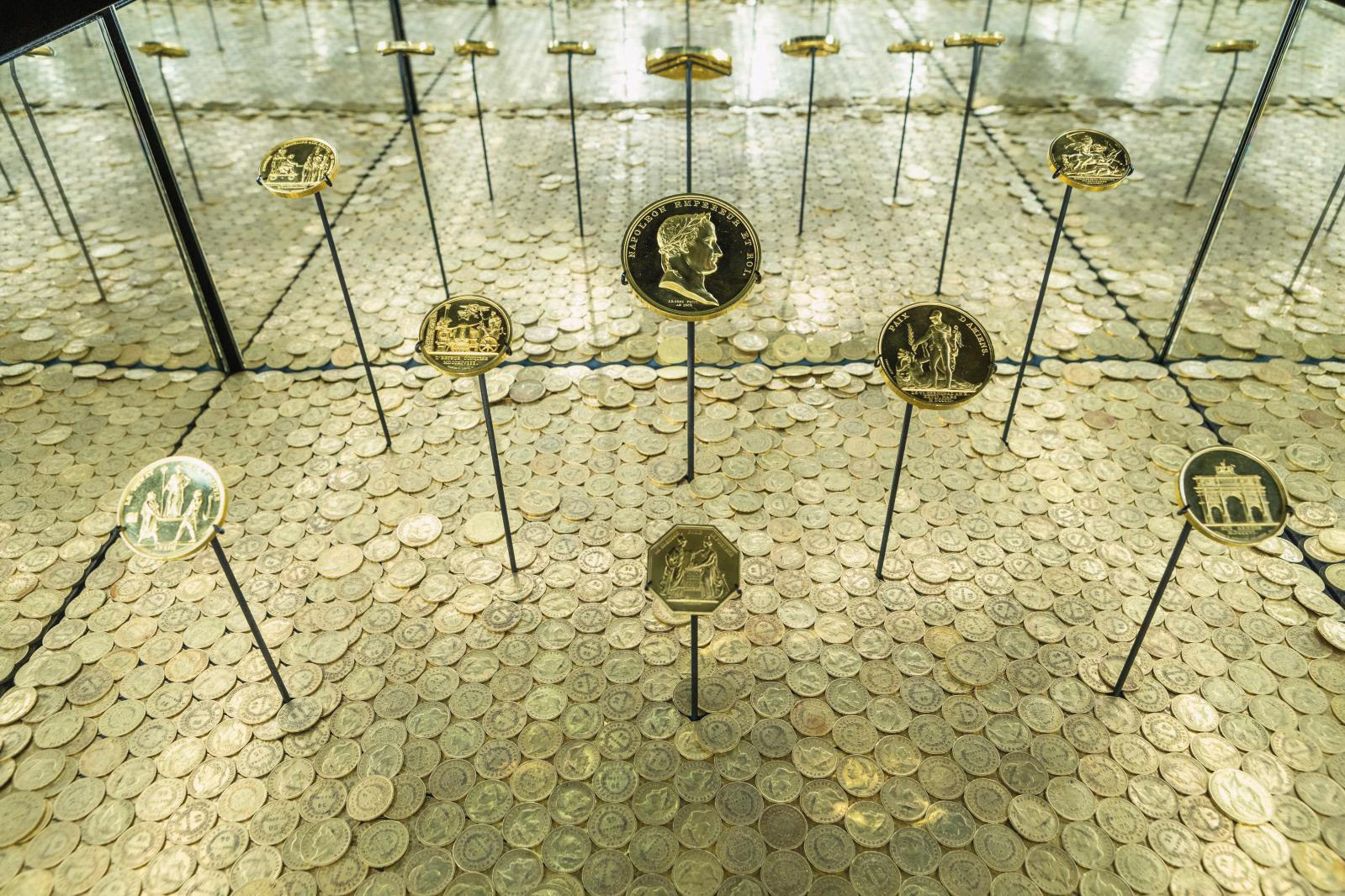 Napoleonic medals on a carpet of 2,021 napoleons for the exhibition at the Grande Halle de La Villette. In the foreground, the eight-sided