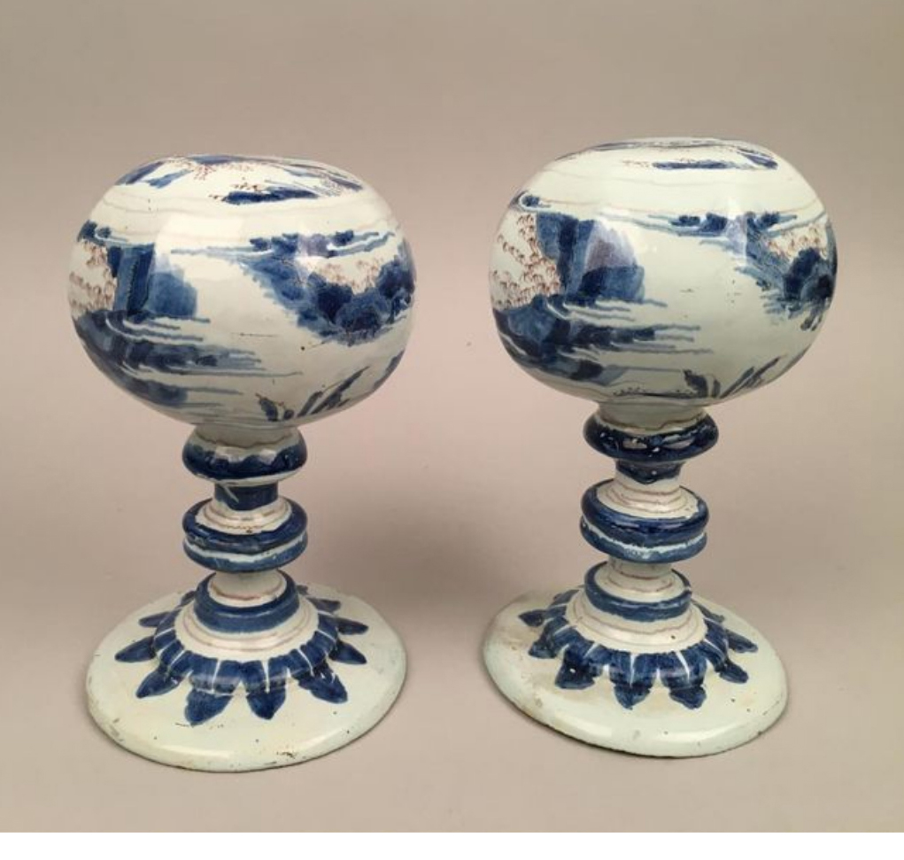 €3,780Nevers, c. 1680. Pair of blue and manganese faïence wig stands decorated with Chinese figures in lake landscapes, h. 18 and 19 cm/7.