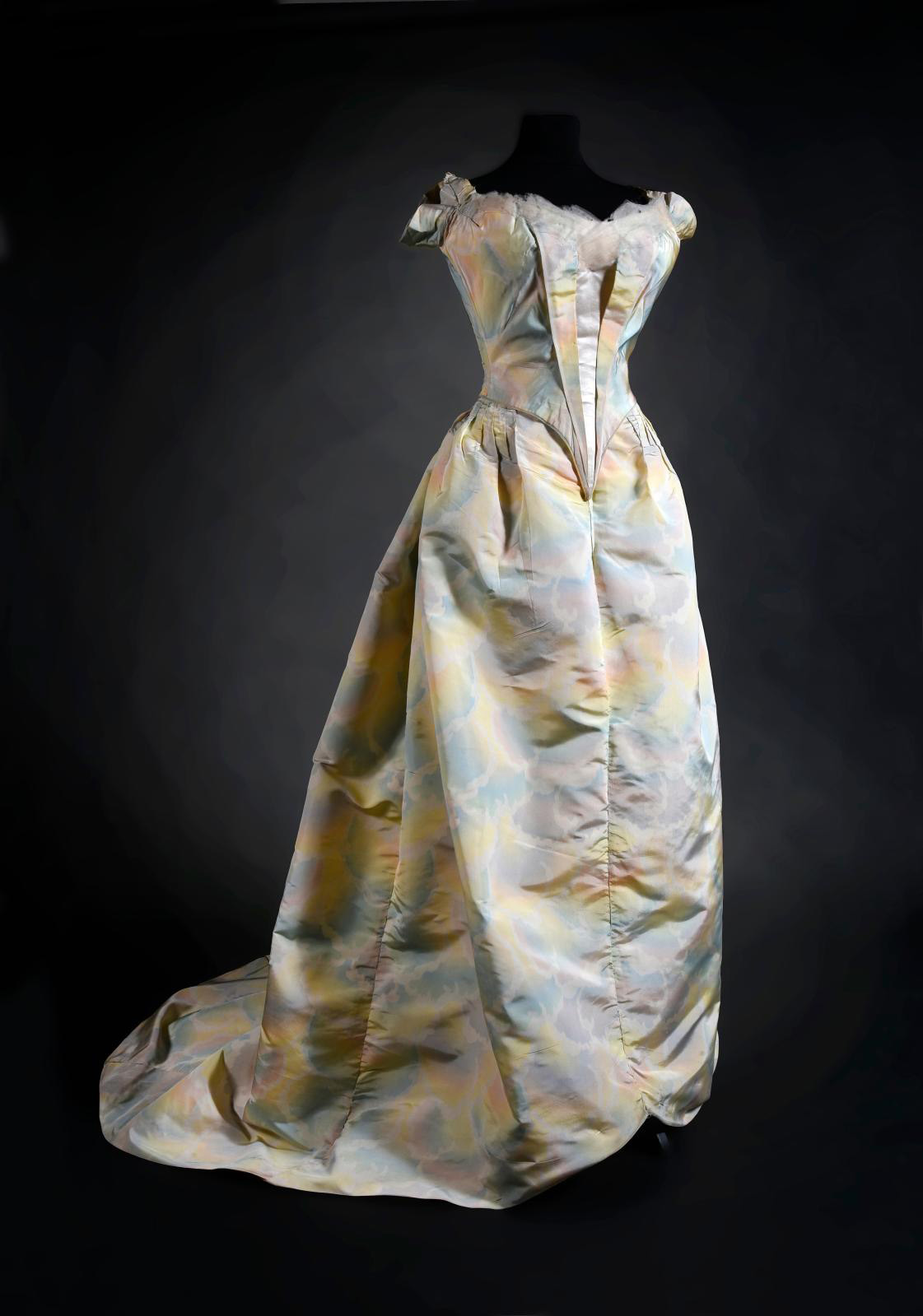 Ball gown by Worth, c. 1900, cream silk faille warp-print dress with iridescent rainbow cloud pattern, boned pointed bodice laced at the b